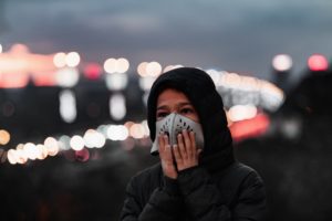 Air Pollution Concept - Young Person with Breathing Mask in the City